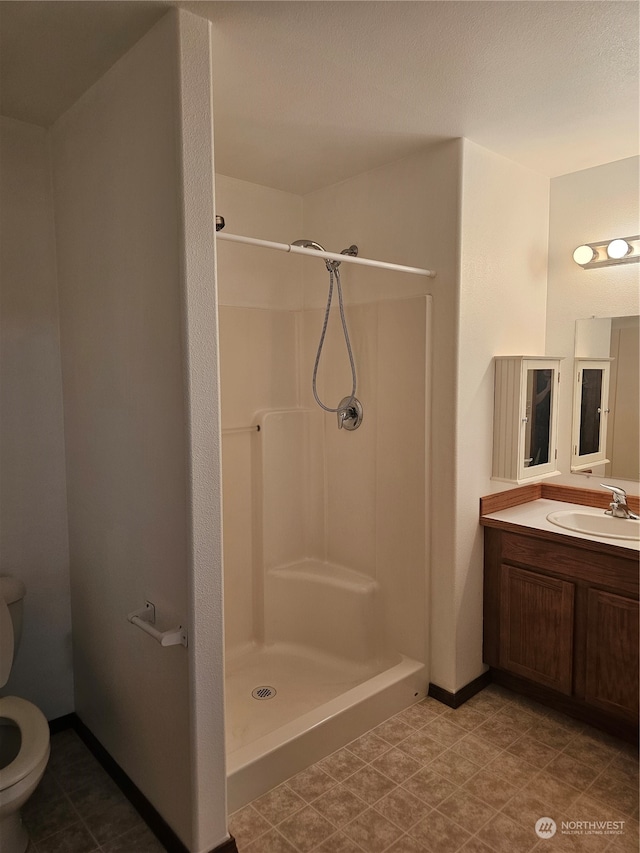 bathroom with tile patterned flooring, vanity, walk in shower, and toilet