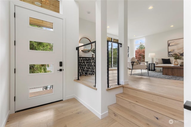 foyer entrance with light wood-style flooring, stairway, baseboards, and recessed lighting