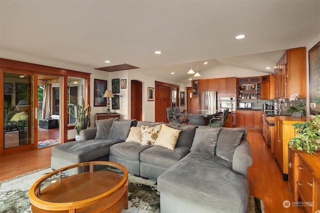 living room with light hardwood / wood-style floors and vaulted ceiling