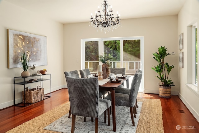 dining area featuring dark wood-type flooring, plenty of natural light, and an inviting chandelier