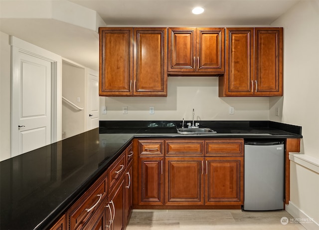 kitchen featuring light hardwood / wood-style flooring, sink, dark stone counters, and stainless steel dishwasher