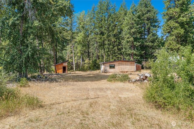 view of yard with an outdoor structure and a view of trees