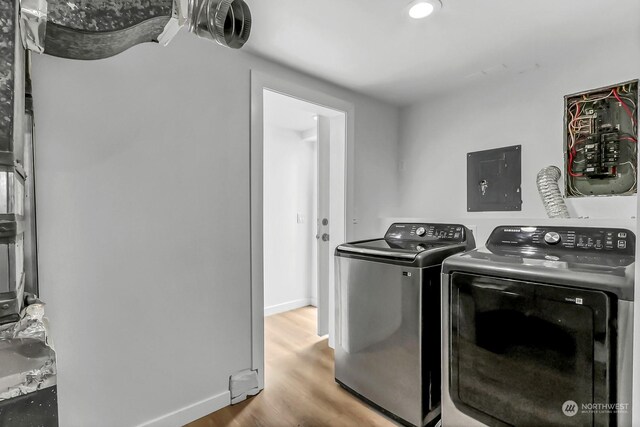 laundry area featuring electric panel, hardwood / wood-style flooring, and washer and dryer