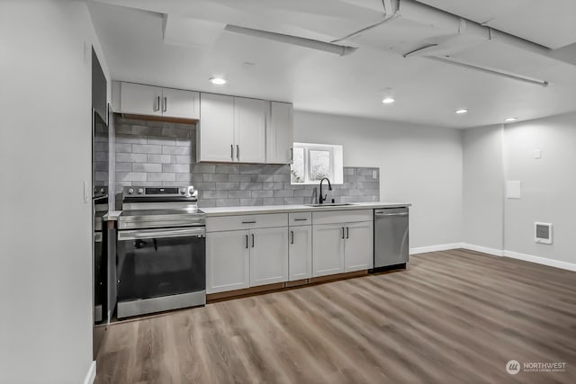 kitchen featuring appliances with stainless steel finishes, sink, wood-type flooring, and tasteful backsplash