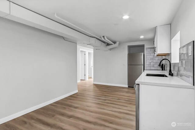 kitchen featuring sink, hardwood / wood-style flooring, tasteful backsplash, white cabinetry, and stainless steel fridge