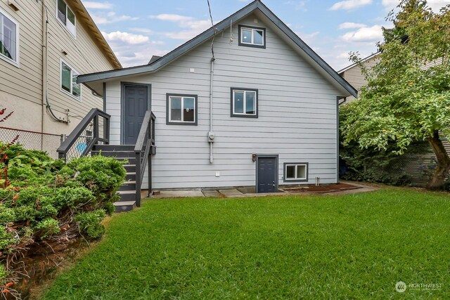 rear view of property featuring a lawn