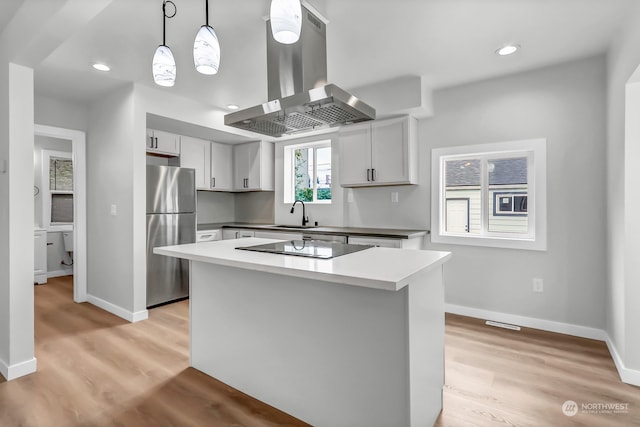 kitchen with decorative light fixtures, island range hood, stainless steel refrigerator, light wood-type flooring, and a center island