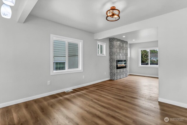 unfurnished living room featuring hardwood / wood-style flooring and a tiled fireplace