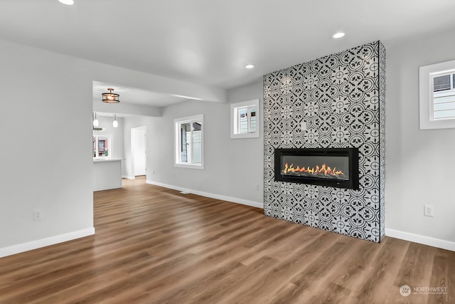 unfurnished living room featuring a tiled fireplace and hardwood / wood-style floors