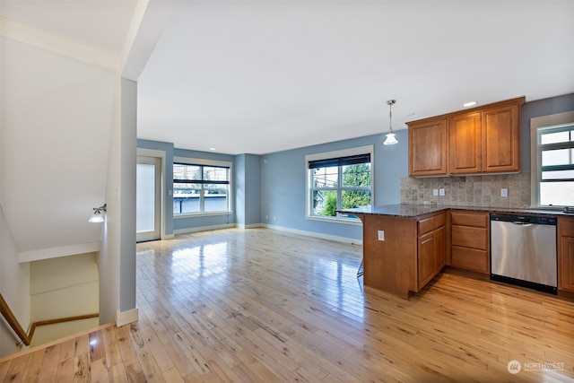 kitchen with dark stone counters, light wood-type flooring, decorative backsplash, stainless steel dishwasher, and kitchen peninsula