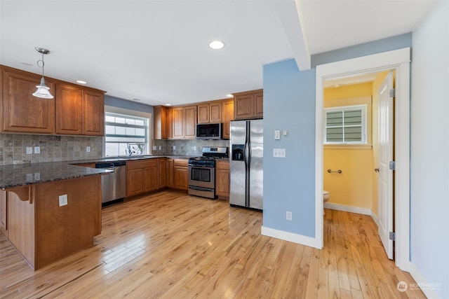 kitchen with light wood-type flooring, appliances with stainless steel finishes, and decorative backsplash