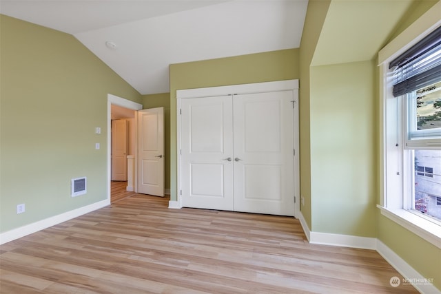 unfurnished bedroom with lofted ceiling, light hardwood / wood-style flooring, a closet, and multiple windows