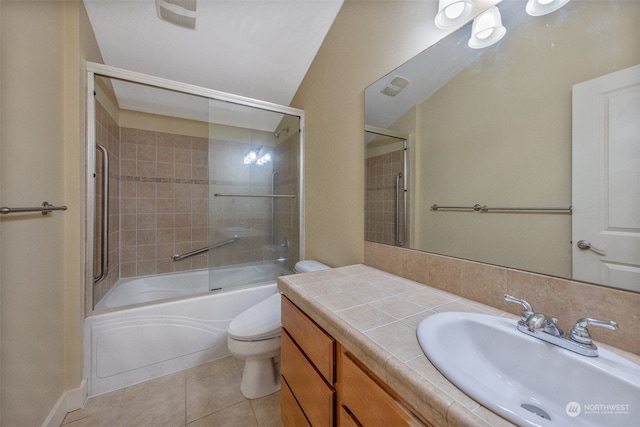 full bathroom featuring combined bath / shower with glass door, tile patterned flooring, vanity, and toilet