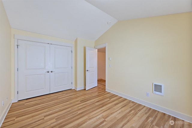 unfurnished bedroom with a closet, vaulted ceiling, and light hardwood / wood-style floors