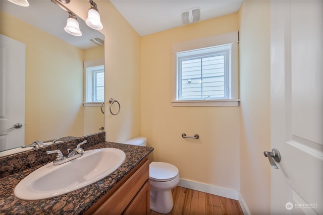 bathroom featuring a wealth of natural light, wood-type flooring, vanity, and toilet