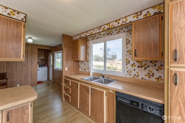 kitchen featuring wood walls, dishwasher, light hardwood / wood-style floors, sink, and washer / dryer