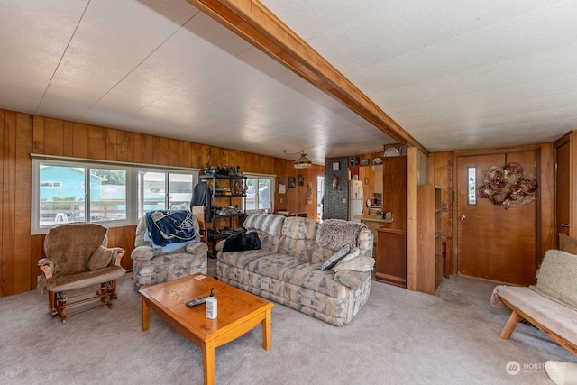 carpeted living room featuring wood walls and beam ceiling