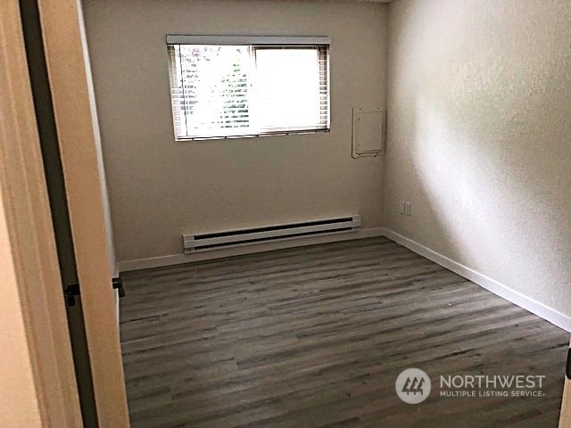 12602 NE 118th St, Kirkland, WA 98034 - spare room with baseboards, dark wood-style flooring, and a baseboard radiator