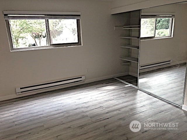 12602 NE 118th St, Kirkland, WA 98034 - unfurnished bedroom with a closet, baseboards, wood finished floors, and baseboard heating