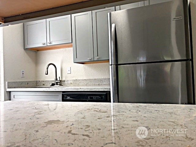 12602 NE 118th St, Kirkland, WA 98034 - kitchen with freestanding refrigerator, black dishwasher, a sink, and light stone counters