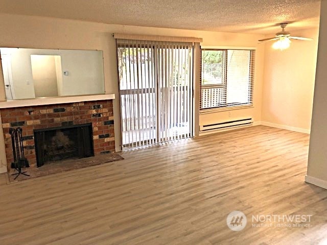 unfurnished living room with a wealth of natural light, ceiling fan, wood-type flooring, and a fireplace