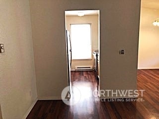 corridor featuring dark wood-type flooring and a baseboard heating unit