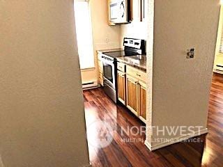 12602 NE 118th St, Kirkland, WA 98034 - kitchen with stainless steel electric range, dark wood-style floors, white microwave, brown cabinetry, and baseboard heating