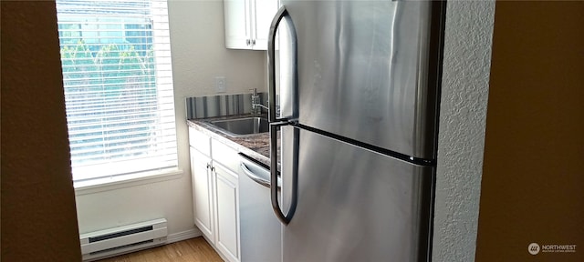 kitchen with a baseboard radiator, stainless steel appliances, plenty of natural light, and white cabinetry