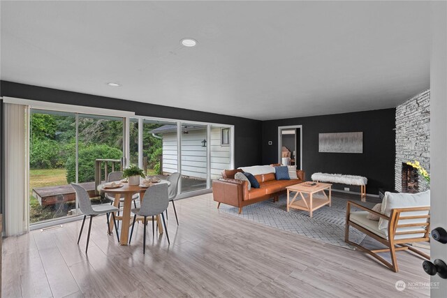 living room with light wood-type flooring, plenty of natural light, and a stone fireplace