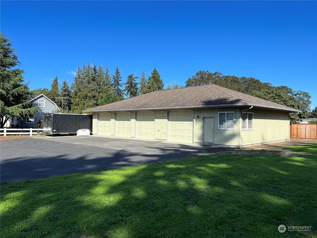 view of side of home with a detached garage, fence, and a lawn