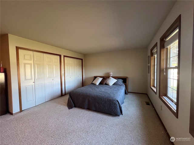 carpeted bedroom with two closets and baseboards
