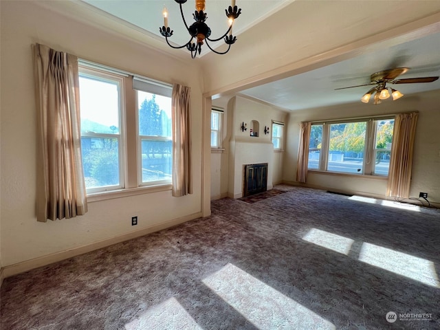 unfurnished living room featuring a healthy amount of sunlight, carpet floors, and ceiling fan with notable chandelier