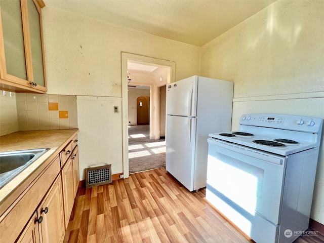 kitchen featuring backsplash, light hardwood / wood-style floors, light brown cabinetry, and white appliances