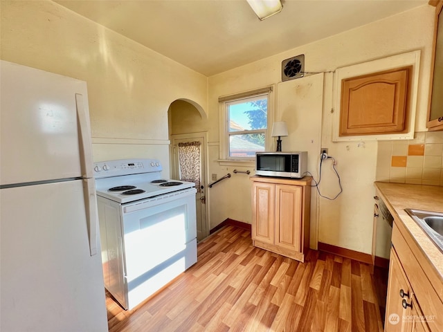 kitchen with light hardwood / wood-style floors, light brown cabinetry, backsplash, and white appliances