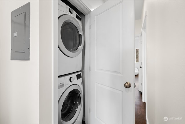 washroom with dark wood-type flooring, electric panel, and stacked washer and dryer