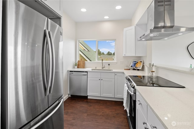 kitchen featuring wall chimney exhaust hood, appliances with stainless steel finishes, white cabinetry, and dark hardwood / wood-style floors