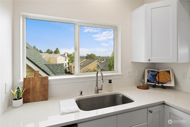 kitchen featuring white cabinetry, sink, and light stone countertops