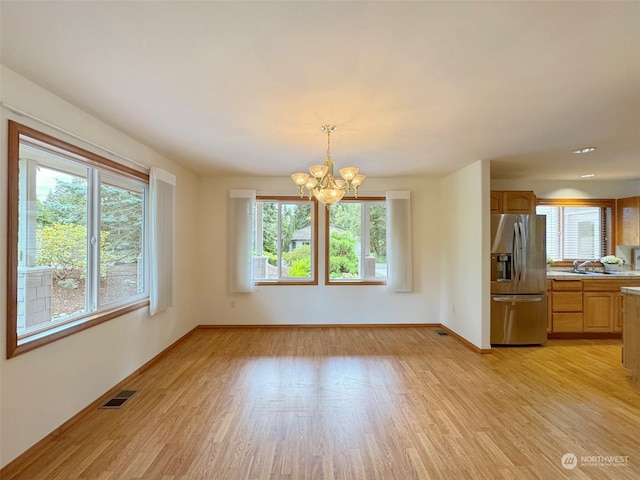 unfurnished dining area featuring light hardwood / wood-style floors and a chandelier