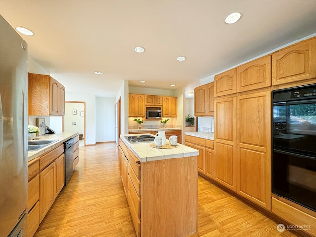 kitchen featuring appliances with stainless steel finishes, a center island, light hardwood / wood-style floors, and sink