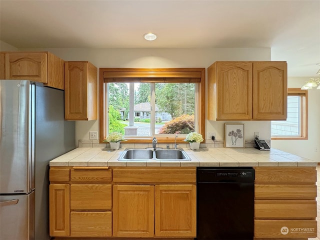 kitchen with black dishwasher, stainless steel fridge, tile counters, and sink