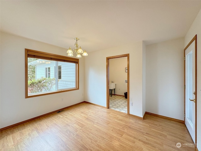 unfurnished bedroom with light hardwood / wood-style floors, a chandelier, and connected bathroom