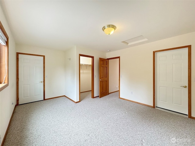 unfurnished bedroom with light colored carpet, a closet, and a walk in closet