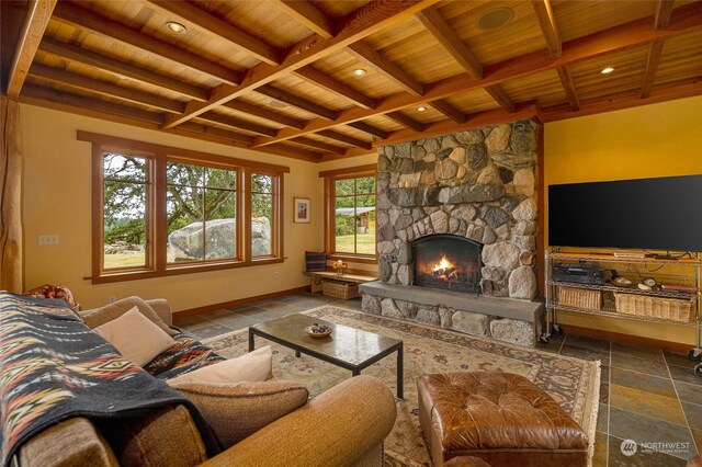 living room with wood ceiling, a stone fireplace, and beam ceiling