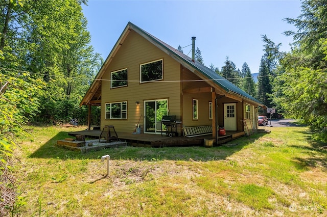 rear view of property with a wooden deck and a yard