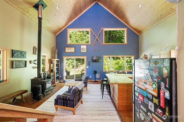 living room featuring high vaulted ceiling, wooden ceiling, and a wood stove