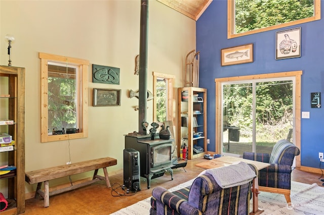 sitting room with a wealth of natural light, high vaulted ceiling, light colored carpet, and a wood stove