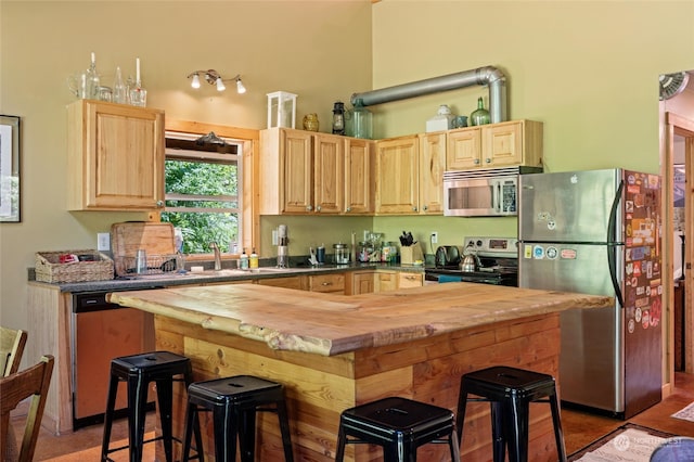 kitchen featuring tile patterned flooring, stainless steel appliances, light brown cabinetry, and butcher block countertops