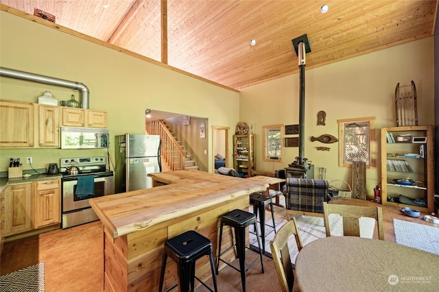 kitchen with stainless steel appliances, light colored carpet, light brown cabinetry, and wood ceiling