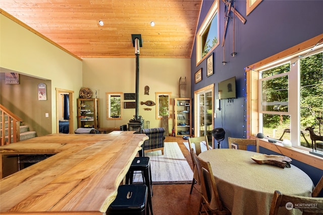 carpeted dining room featuring a wealth of natural light, high vaulted ceiling, and wooden ceiling