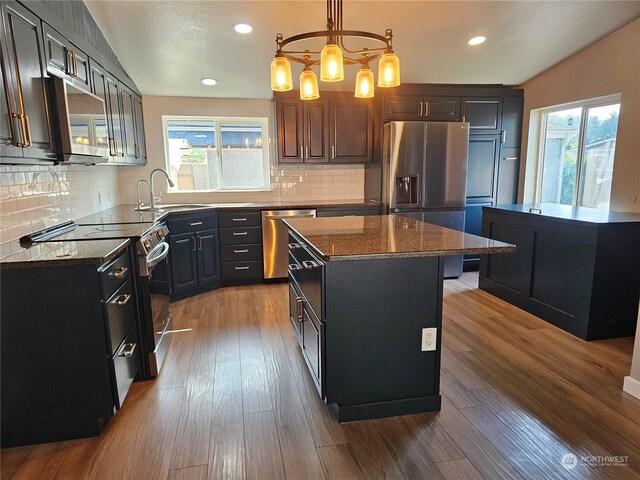 kitchen with decorative backsplash, pendant lighting, hardwood / wood-style flooring, sink, and stainless steel appliances